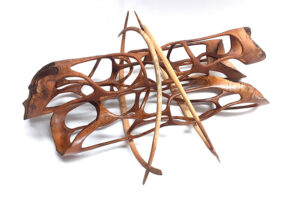 Abstrakte Holzskulptur mit organischen Durchbrüchen und gebogenen, spitz zulaufenden Holzelementen auf weißem Hintergrund.